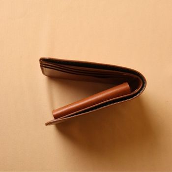 Brown leather wallet on a matching beige background
