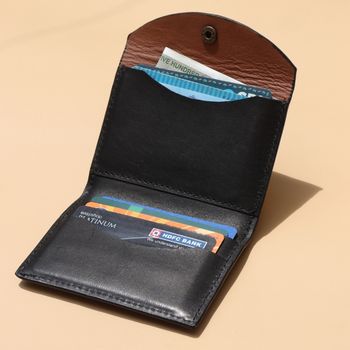 Black leather wallet with open flap showing cards on a beige background