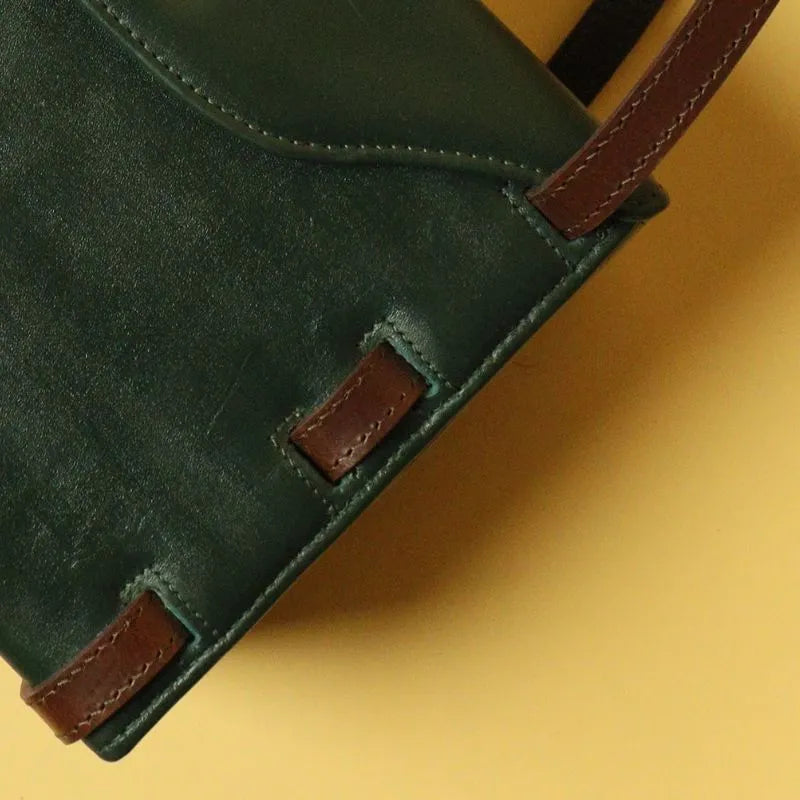 Detail image of a dark green leather structured crossbody sling handbag with intertwined dark brown leather straps