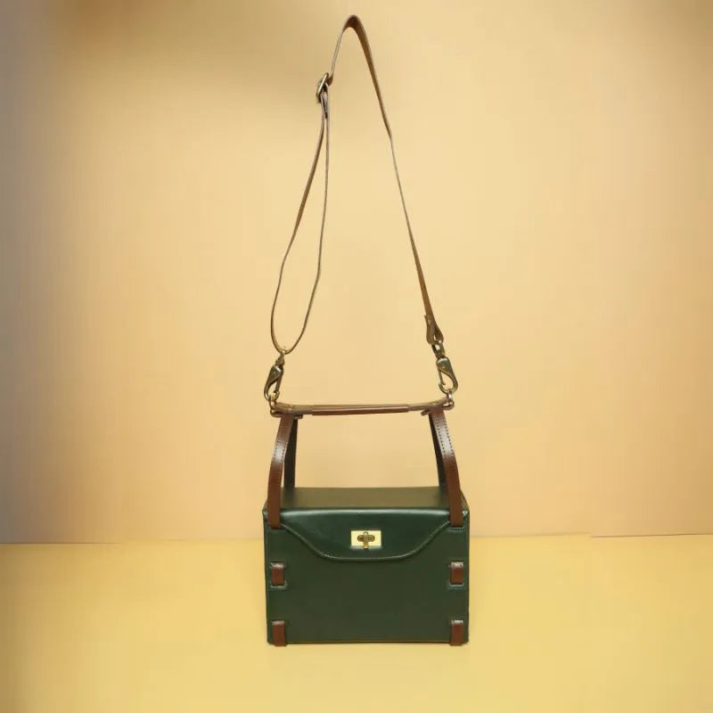 A Dark Green Leather Structured Crossbody Sling bag with a dark green body, fully extended dark brown leather straps and handle and a a light gold twist lock closure