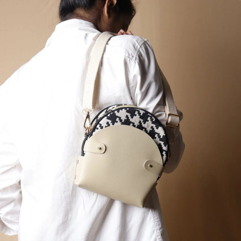 Rear View of Woman in white shirt carrying a canvas bag with black and white houndstooth weave inside a off-white leather case over her shoulder
