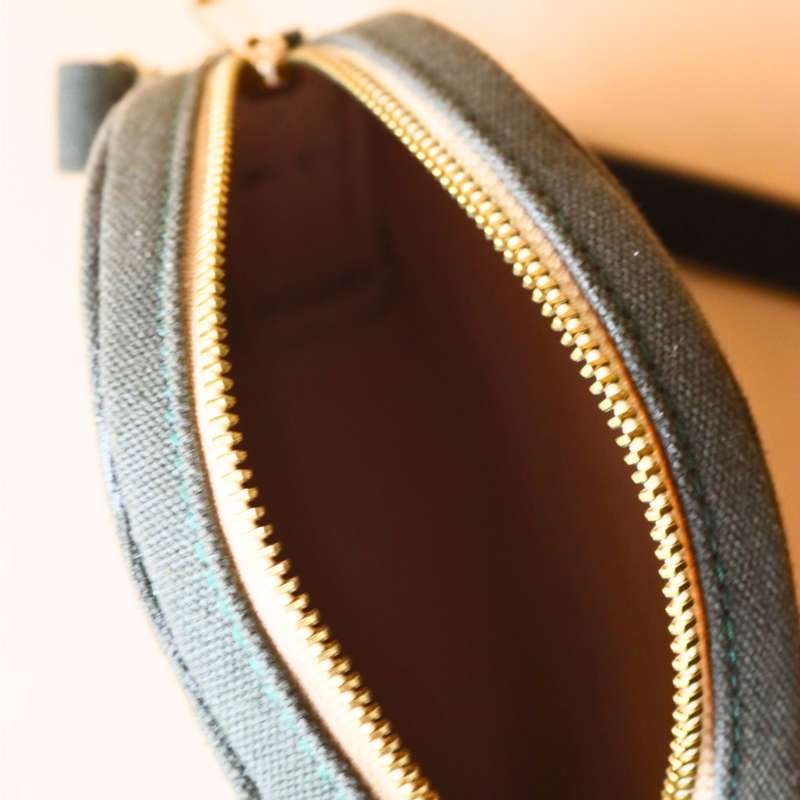 Internal top view of a Dark Green Canvas Crossbody sling bag in a maroon leather case with soft felt lining