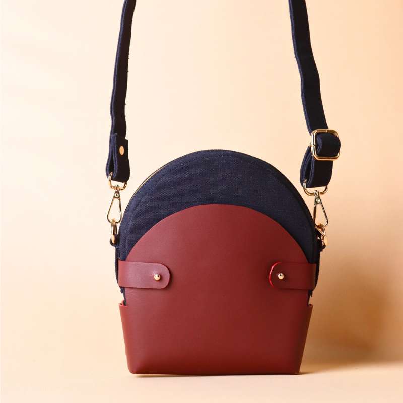 Front view of a Deep Blue Canvas Crossbody sling bag in a maroon leather case with its canvas strap extended
