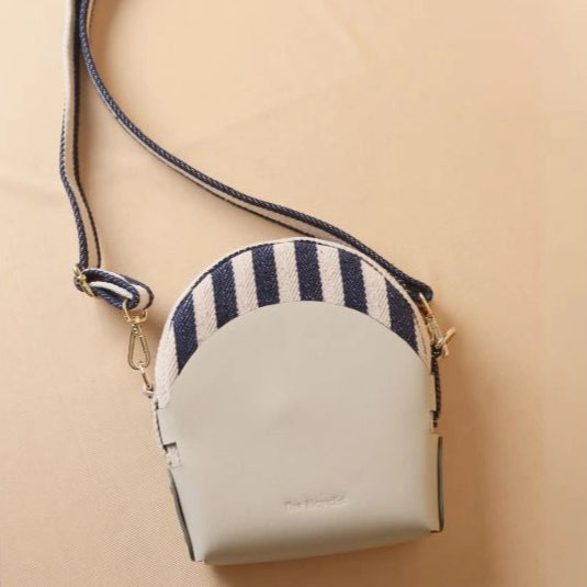 Back View of a stirpe canvas crossbody sling bag in a off-white leather case with its canvas straps extended
