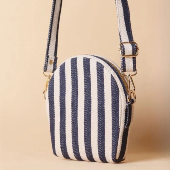 Back View of a stirpe canvas crossbody sling bag in a off-white leather case with its canvas straps extended