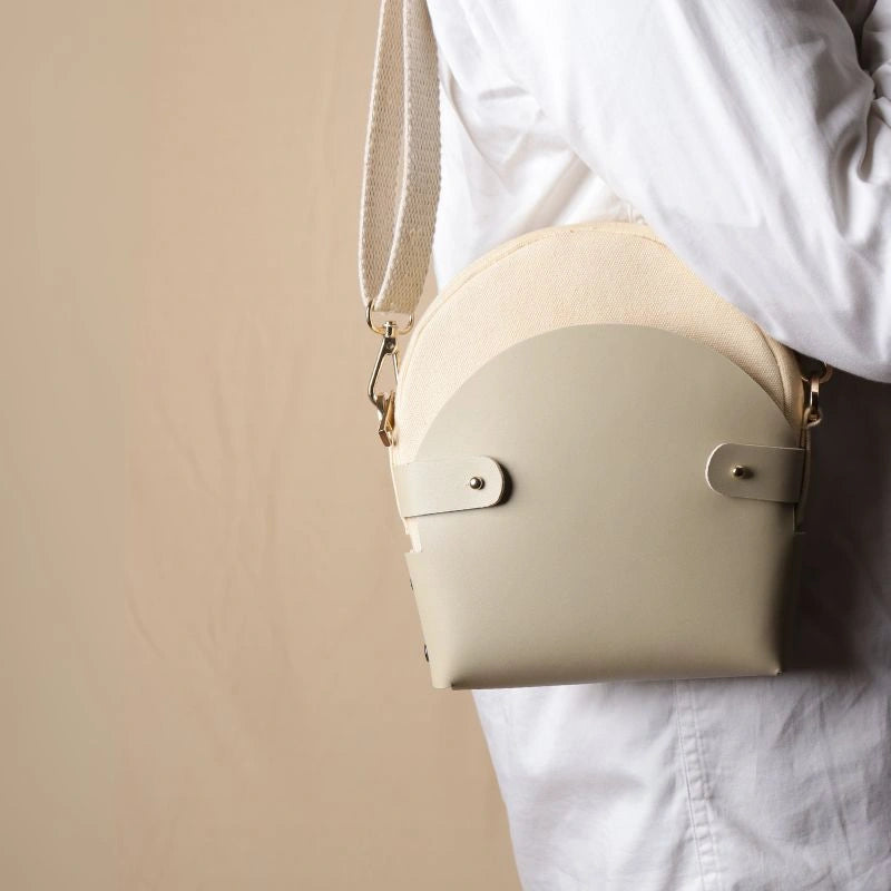 Woman In a white shirt carrying a off-white canvas crossbody shoulder sling in a 0ff-White Leather Case on her shoulder as a shoulder bag