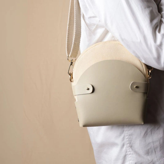 Woman In a white shirt carrying a off-white canvas crossbody shoulder sling in a 0ff-White Leather Case on her shoulder as a shoulder bag