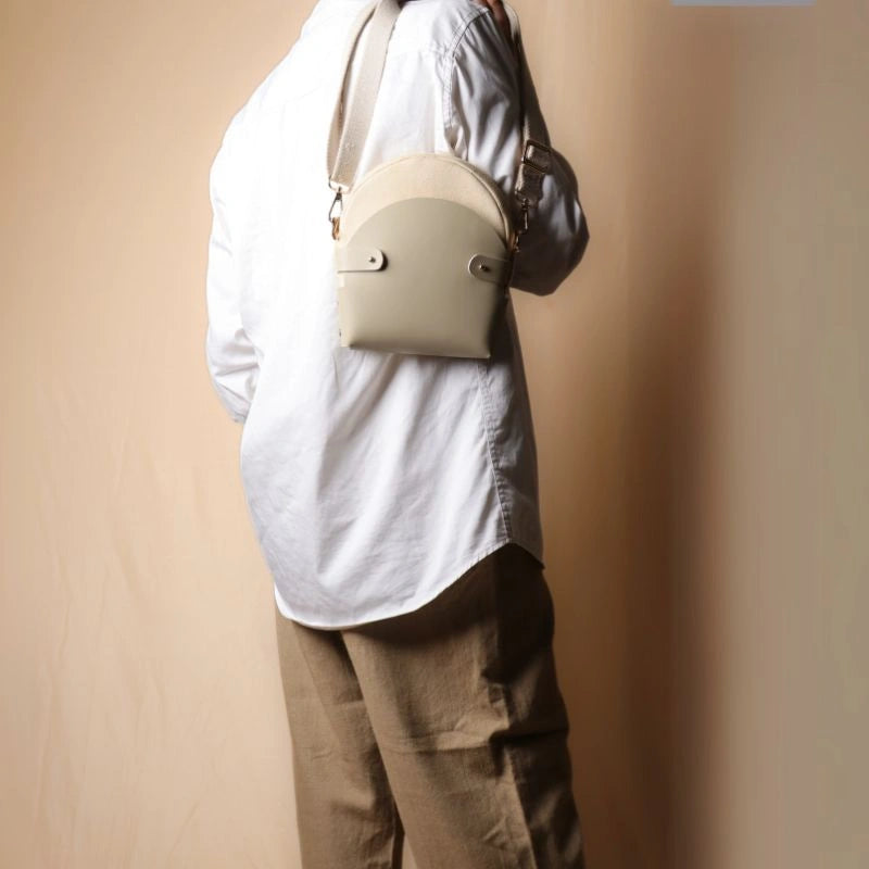 Woman In a white shirt carrying a off-white canvas crossbody shoulder sling in a 0ff-White Leather Case over her shoulder