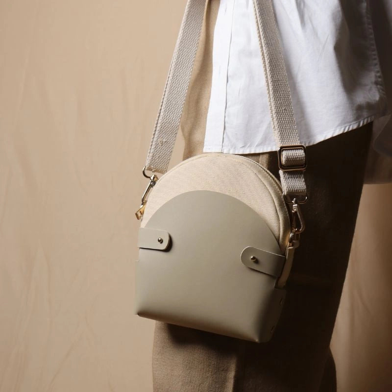 Woman In a white shirt carrying a off-white canvas crossbody shoulder sling in a 0ff-White Leather Case in her hand