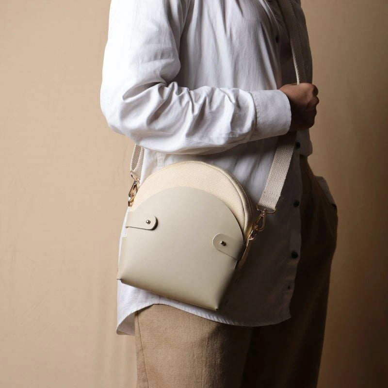 Woman In a white shirt carrying a off-white canvas crossbody shoulder sling in a 0ff-White Leather Case over her shoulder as a crossbody