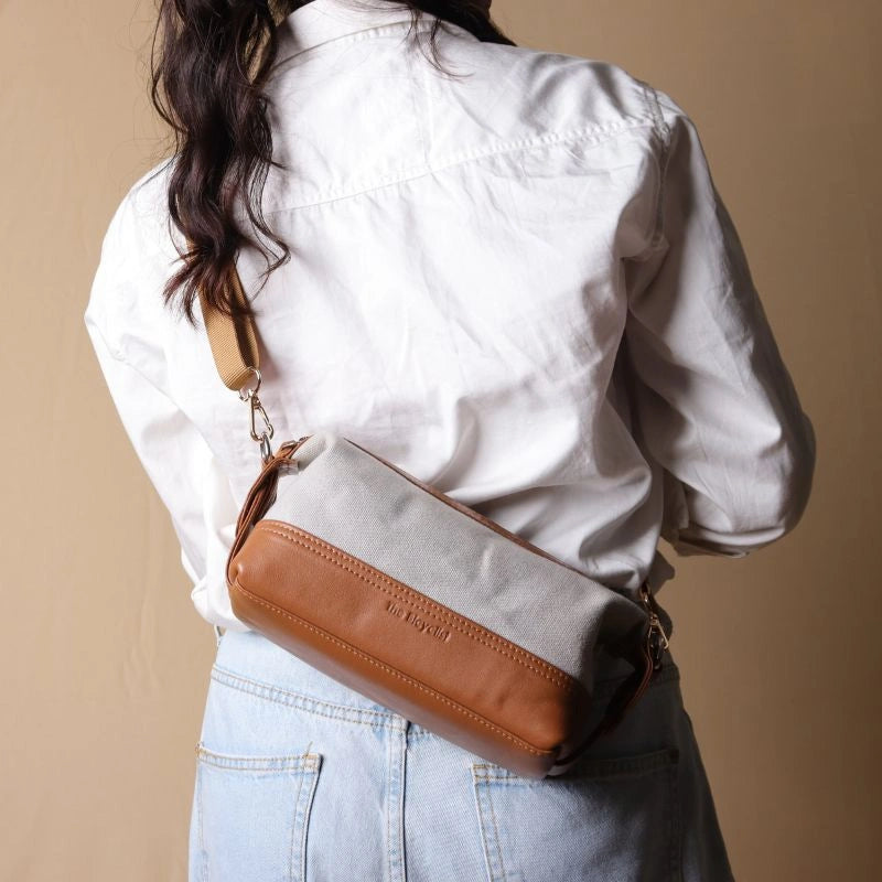 Back View of Woman in a white shirt carrying a Grey canvas and tan leather pouch as a side sling across her shoulder