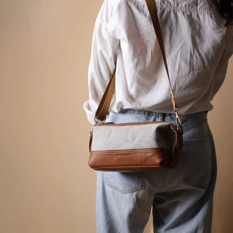 Woman in a white shirt carrying a Grey canvas and tan leather pouch as a side sling on her shoulder