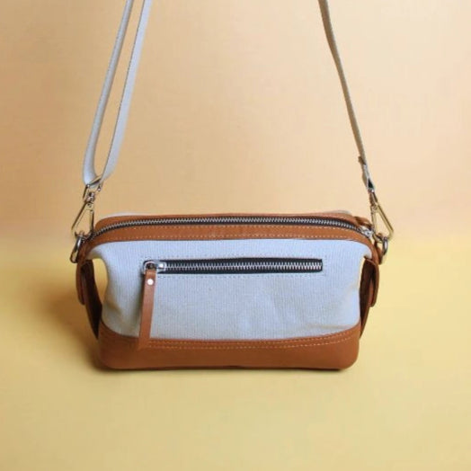 Front view of zipped grey cotton canvas and tan leather dopp kit with extended straps