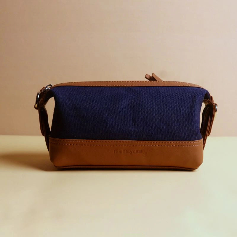 Front view of a navy blue cotton canvas and tan leather dopp kit with zip
