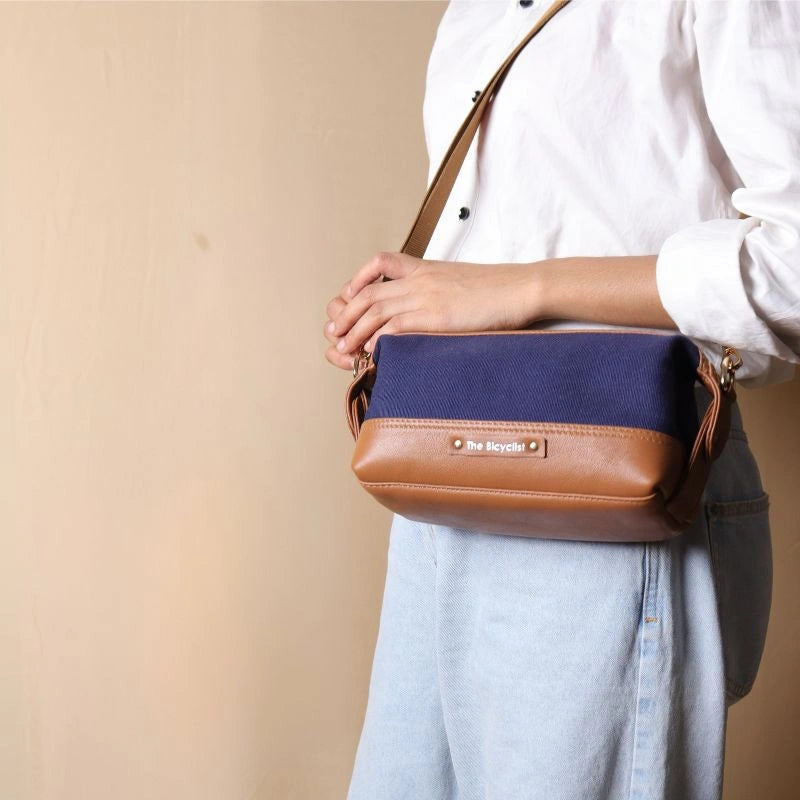 Woman in a white shirt carrying a Navy Blue canvas and tan leather pouch as a side sling across her shoulder