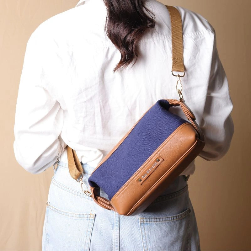 Woman in a white shirt carrying a Navy Blue canvas and tan leather pouch as a side sling across her shoulder