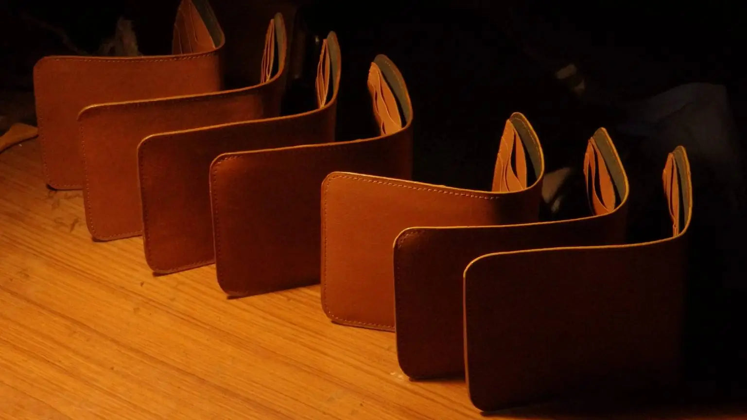 A row of Handmade Leather Wallets in Tan under the light of a lamp