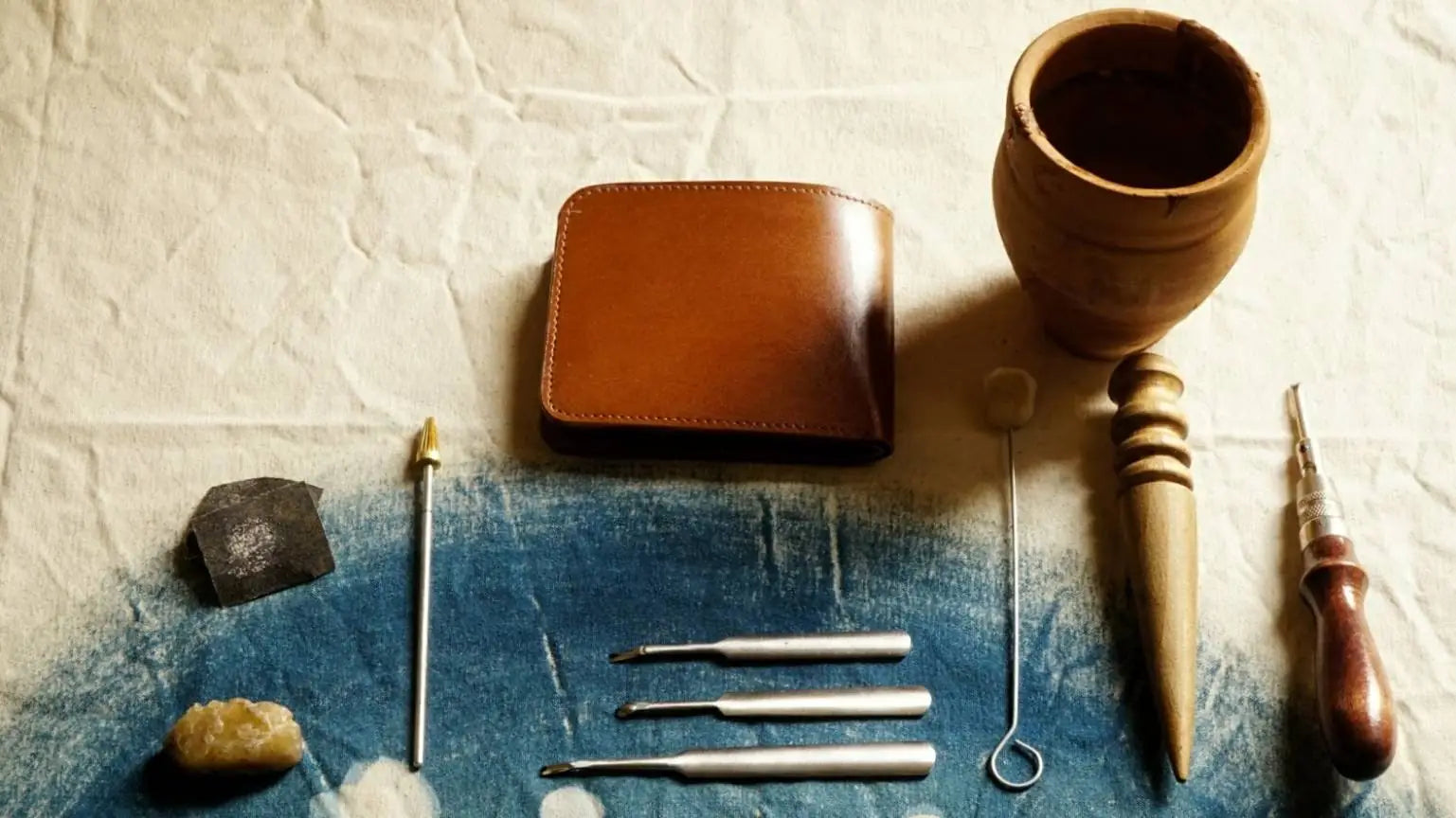 Tan Leather Wallet with tools that used in hand crafting the leather wallet.