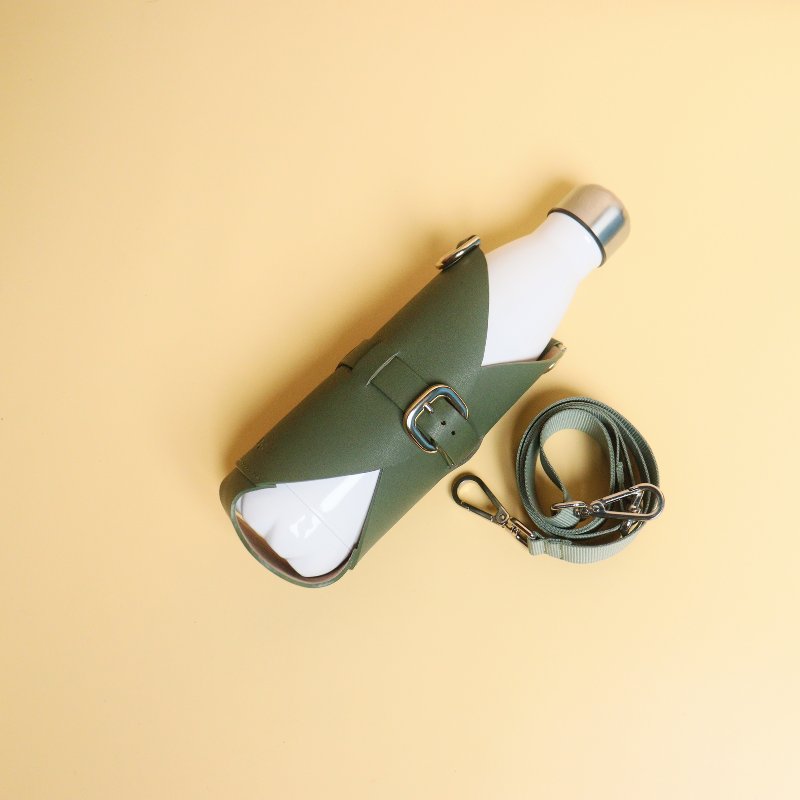 Leather one liter bottle carrier case in Dark Green with chrome plated finish metal fittings and a removable and adjustable nylon strap along with a white bottle front flat image