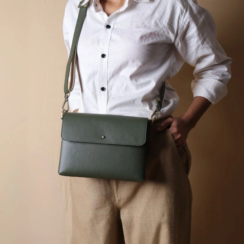 Front view of Woman in a white shirt carrying a mint green leather crossbody shoulder bag with a flap across her shoulder