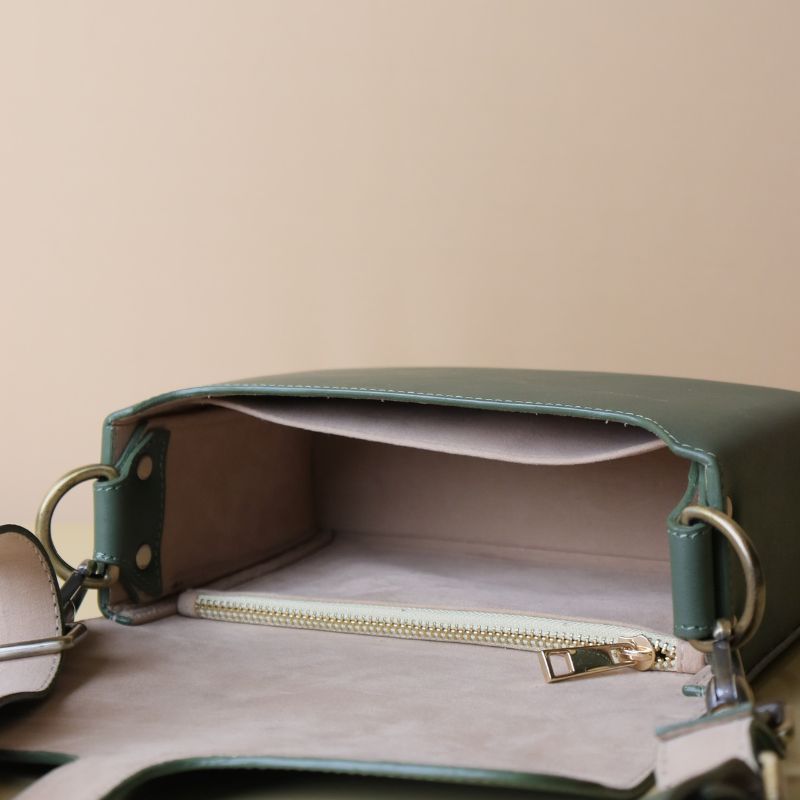 Olive green handmade leather women's crossbody structured sling bag with brass finished metal fittings and adjustable strap open view