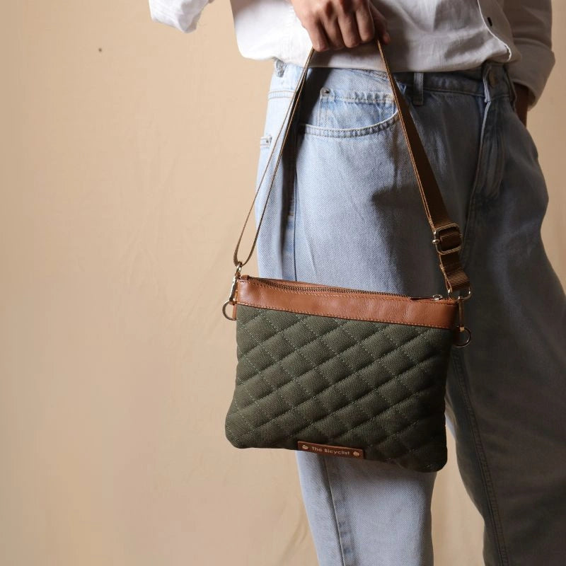 Woman holding a quilted cotton canvas sling bag with leather trims and zipped closure in her hand