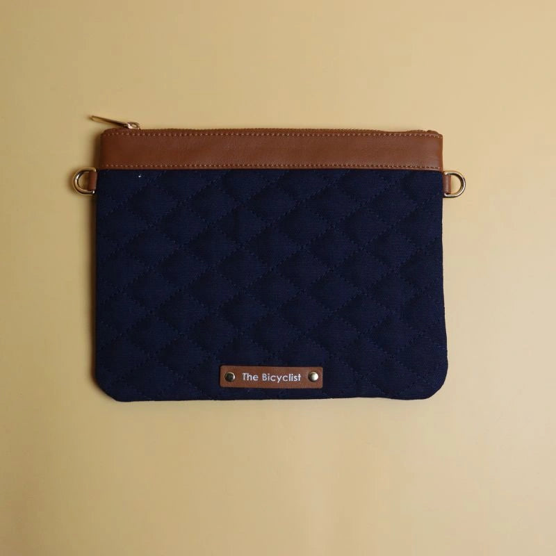 Top view of a quilted navy blue canvas and leather sling bag with zip