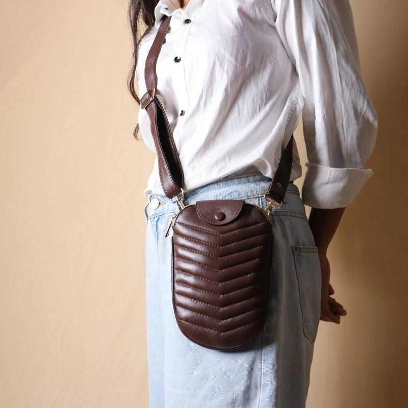 Woman in a white shirt wearing a dark brown quilted leather crossbody sling purse across her body