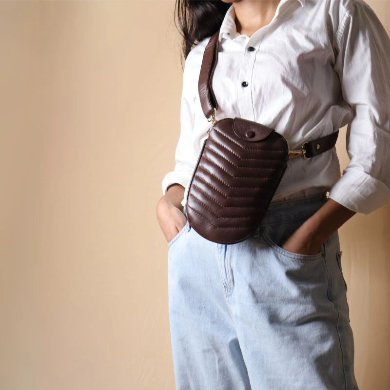 Woman in a white shirt wearing a quilted leather crossbody sling pouch bag across her chest