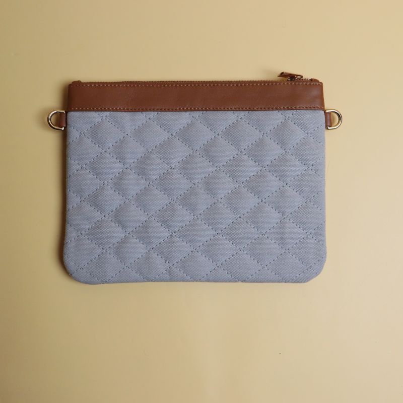 Small Crossbody Sling Pouch for Women with a Quilted gray Canvas and Tan Sheep Leather Trimming with a Zip Closure removable and adjustable straps in chrome plated finish Back view