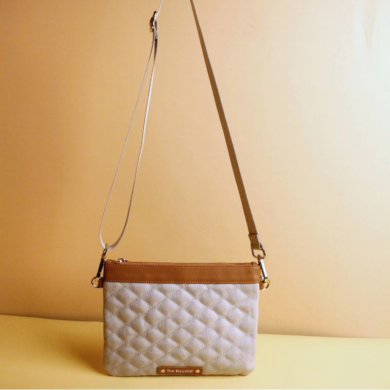 Small Crossbody Sling Pouch for Women with a Quilted gray Canvas and Tan Sheep Leather Trimming with a Zip Closure removable and adjustable straps in chrome plated finish standing view