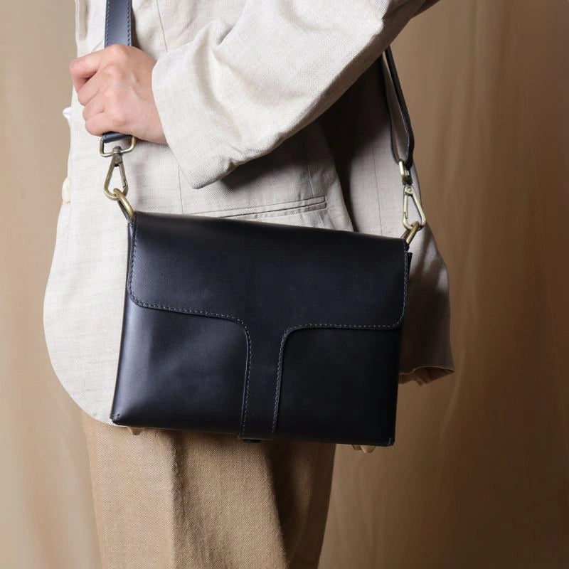 Woman in a off-white blazer carrying a Black Leather Crossbody Shoulder sling Bag with flaps across her shoulder