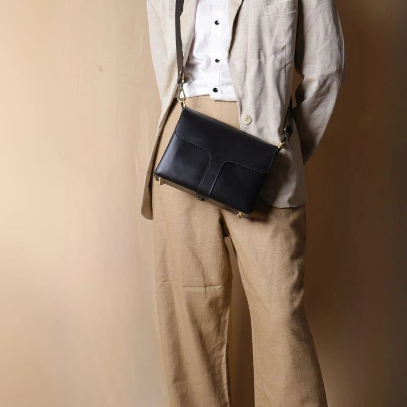 Front Image of Woman in a off-white blazer carrying a Black Leather Crossbody Shoulder sling Bag with flaps across her shoulder