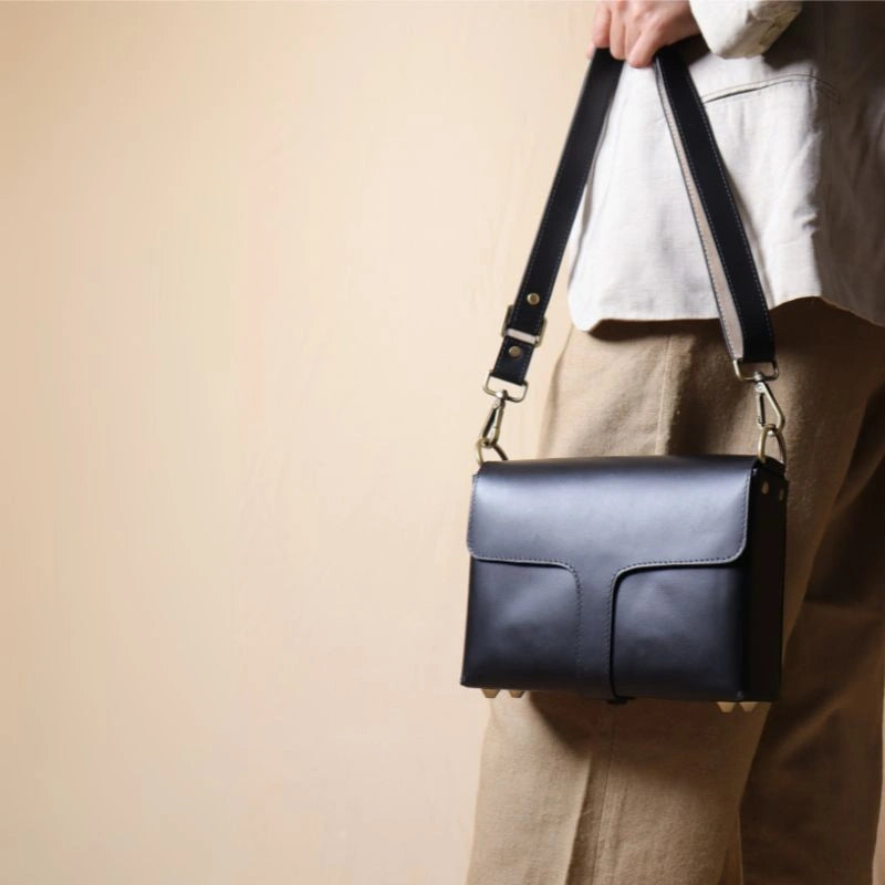 Woman in dark beige trousers carrying a Black Leather Crossbody Shoulder sling Bag with flaps in her hand