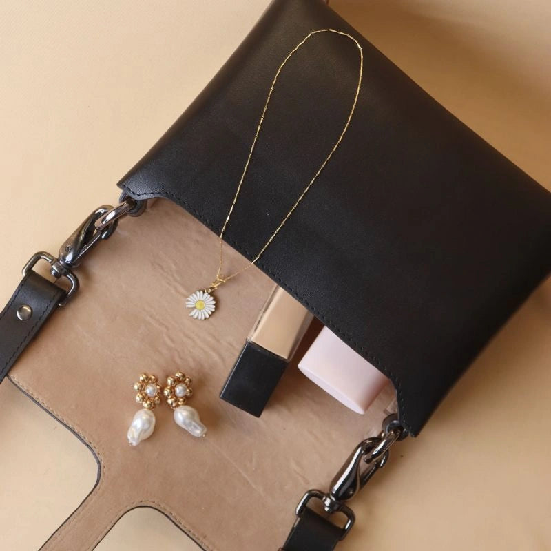 Top open view of black crossbody shoulder sling bag with light beige felt lining.