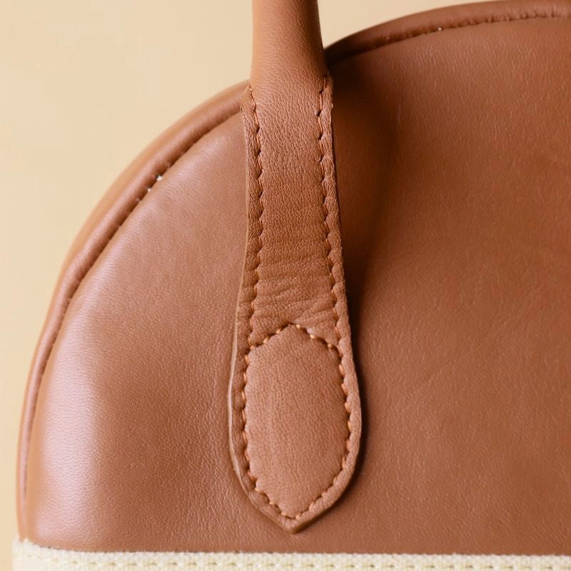 Detailed stitching view of a tan leather top handle