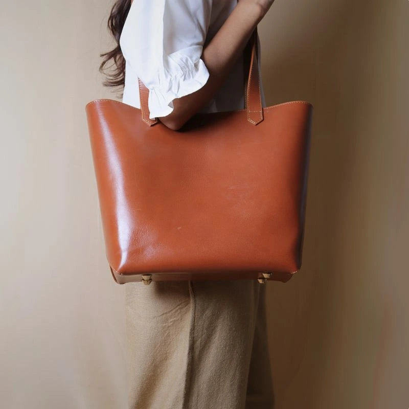 Woman carrying a leather tote handbag in tan on shoulder