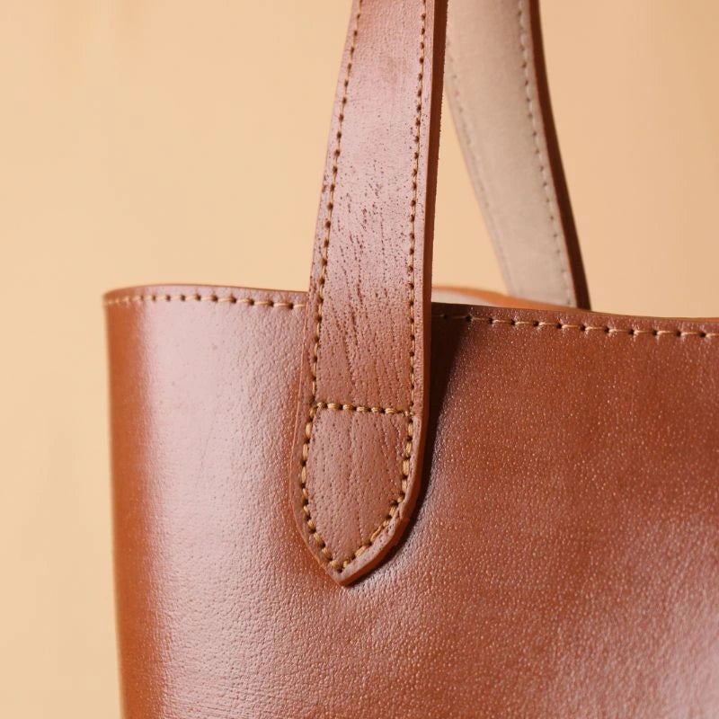 Detailed stitch view of the handle of a tan leather tote bag