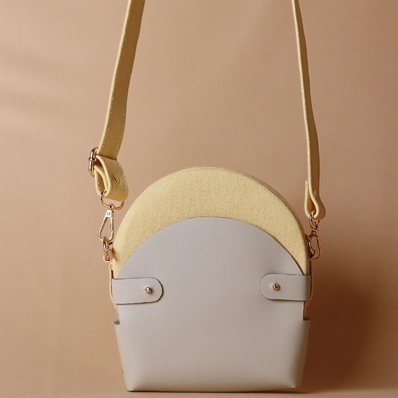 Hancrafted Canvas and Leather slingbag-yellow canvas body with off-white leather case cotton lining-adjustable and removable shoulder straps-gold plated metal fittings-canvas bag and leather case front angle view-The Bicyclist