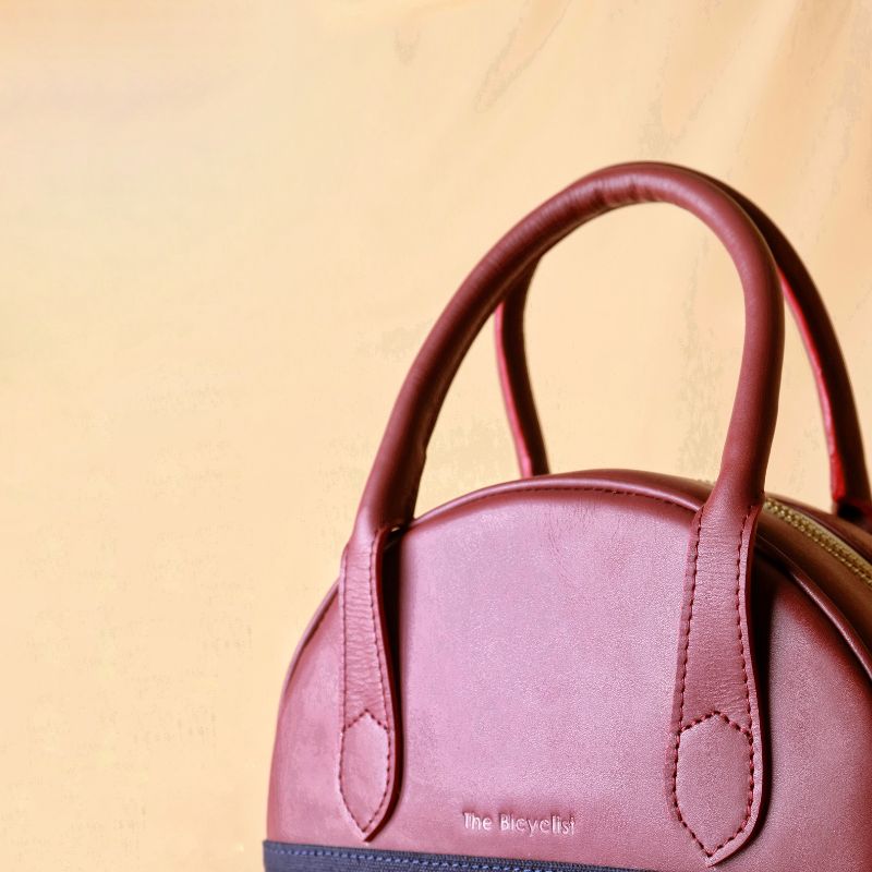 Hancrafted Canvas and Leather handbag-deep blue canvas body with maroon grain leather top-beige felt lining-adjustable and removable white shoulder straps-gold plated metal fittings-top angle view-The Bicyclist