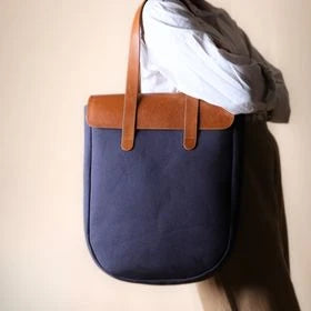 woman in a white shirt carrying a deep blue canvas and tan leather tote