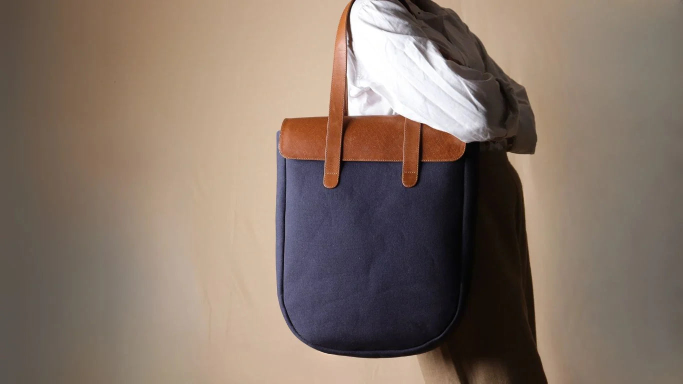 woman in a white shirt carrying a deep blue canvas and tan leather tote