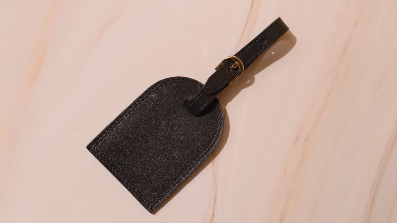 Leather Luggage Tag in Black with Gold Plated Metal Buckle on a off-white background