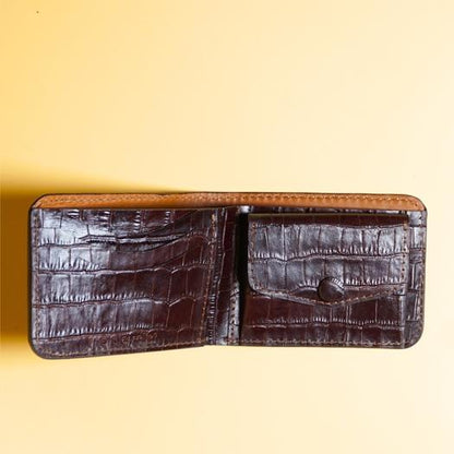 Maroon leather bifold coin pouch wallet with crocodile texture on a yellow background