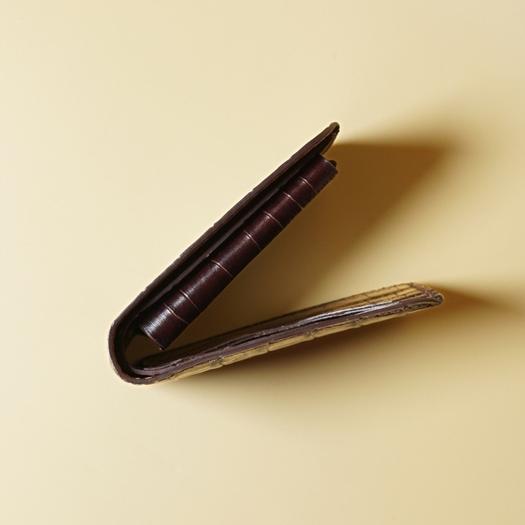 Top View of a Maroon leather bifold wallet with crocodile texture on a beige background