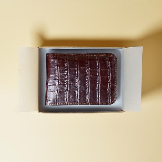 Maroon leather wallet in a box on a beige background