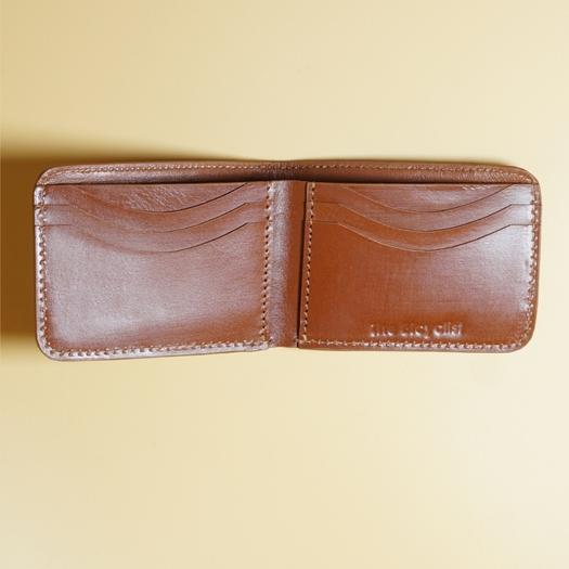 Tan Brown open bifold leather wallet on a beige background