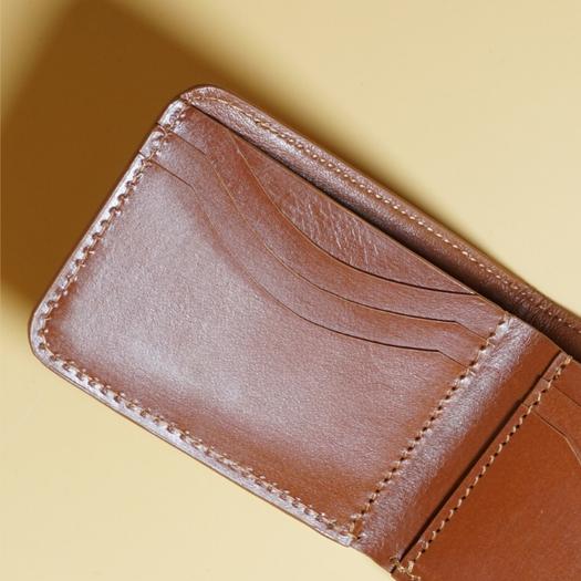 Close-up of a tan brown leather wallet on a beige background