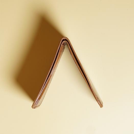 Close up edge of a tan brown leather wallet on a beige background