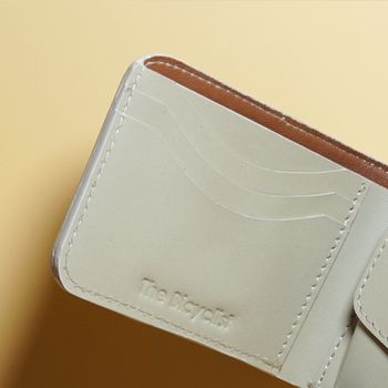 Close-up of a Off White bifold leather wallet with brown interior on a beige background
